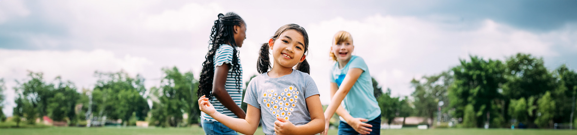  A Daisy, Brownie, and Junior Girl Scout playing in a field 