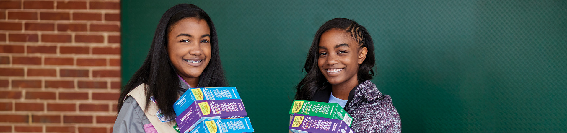  Smiling girl scouts holding a variety of cookie boxes. 