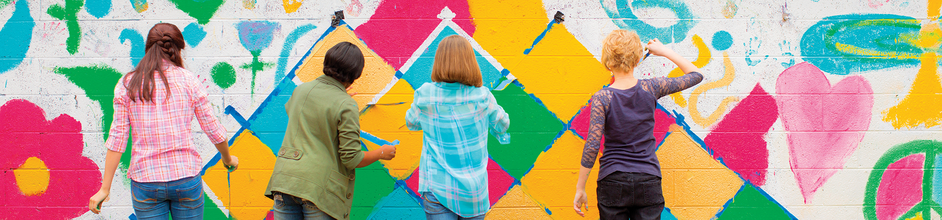  four girls paining a wall in bright colors 