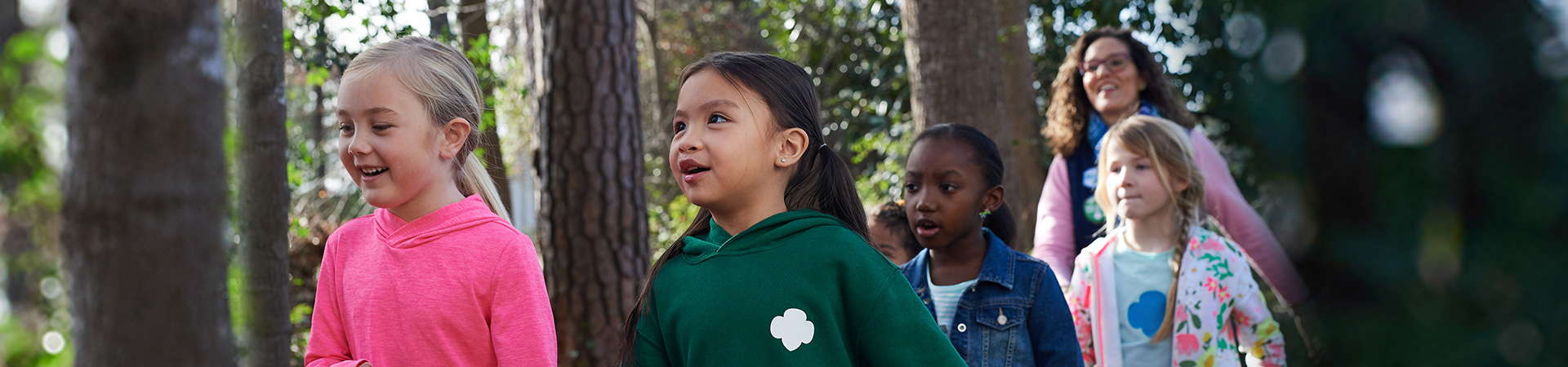  a troop of Daisy Girl Scouts on a hike with their leader 