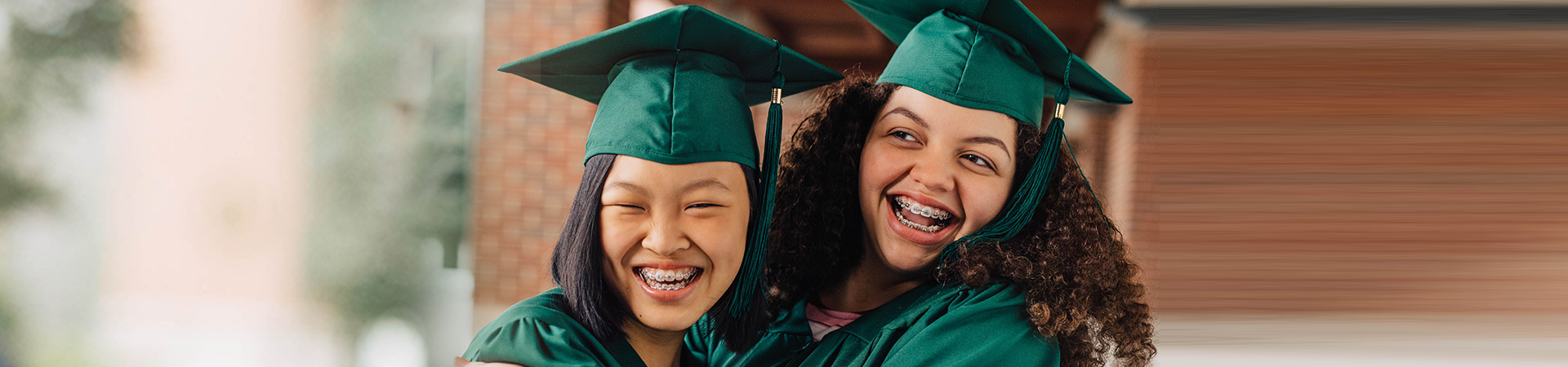  two girls in graduation regalia hugging 