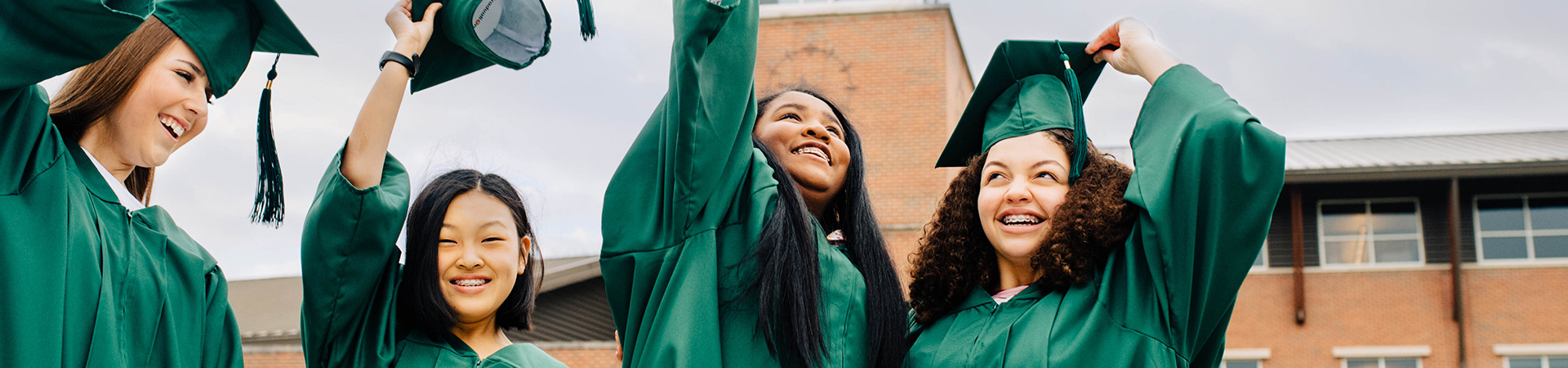  Four girls in their graduation regalia tossing their hats in the air 