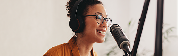  A young woman wearing headphones and talking into a mic. 